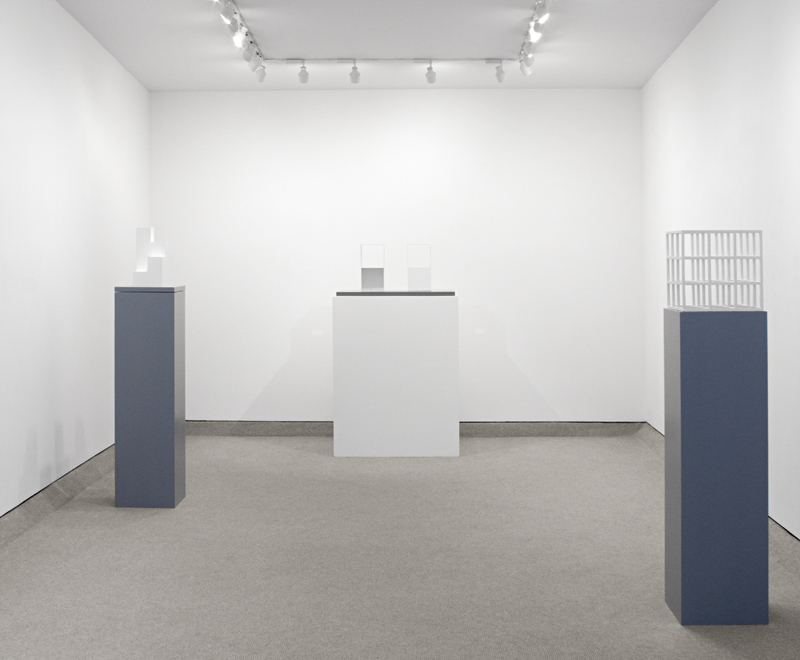 Exhibition view of Sol LeWitt sculptures of various geometric figures on pedestals